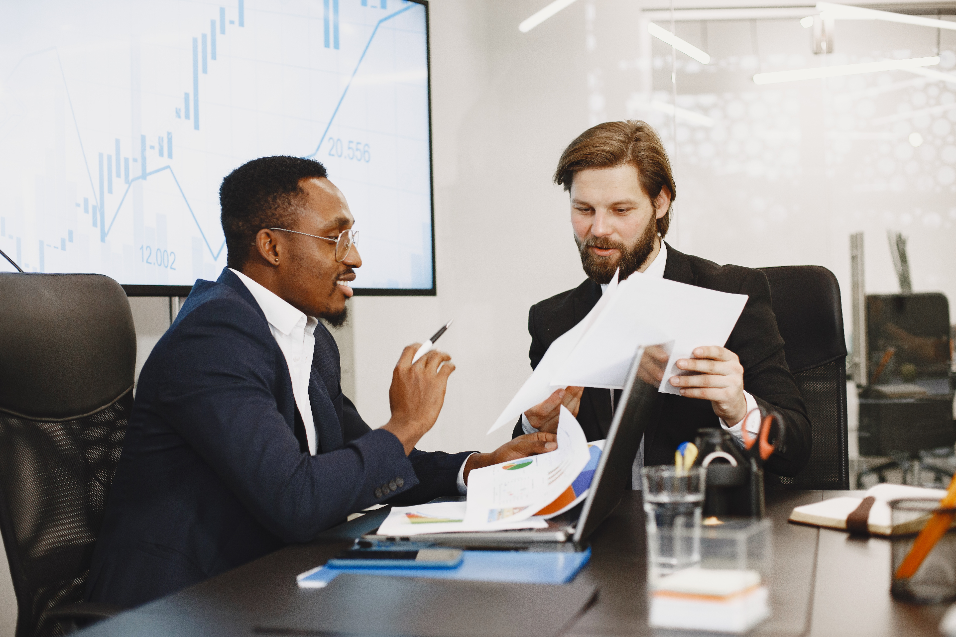 Two business professionals reviewing financial reports and growth dashboards in a strategy meeting